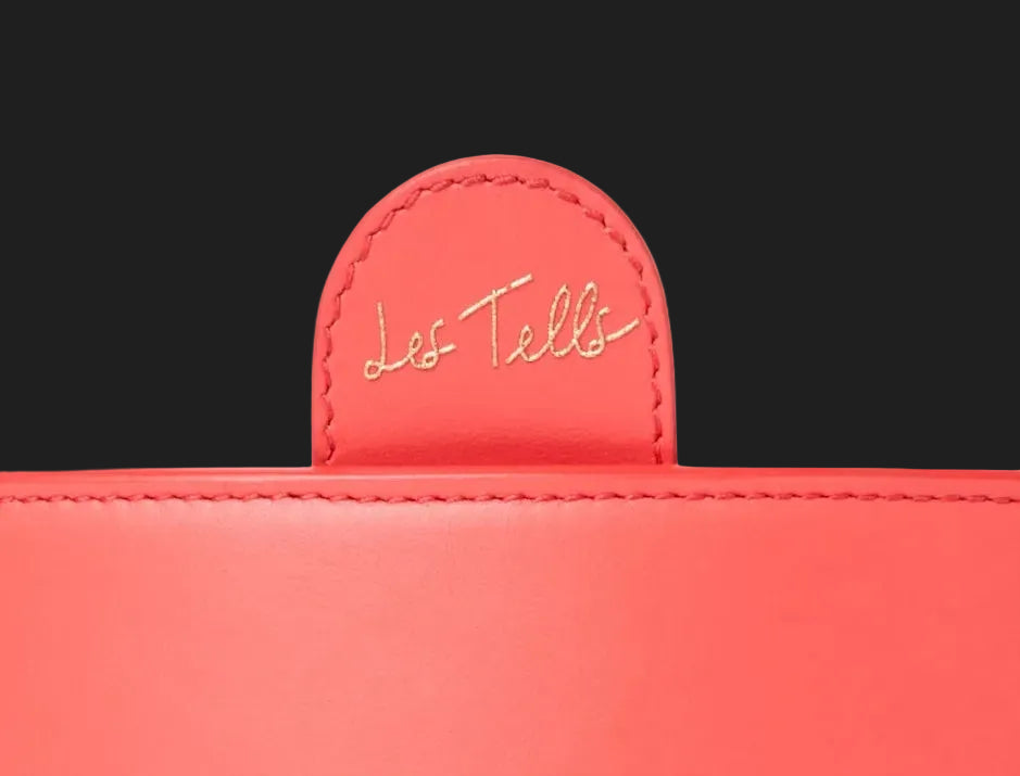 Coral leather bag flap embossed with the Les Tells signature in gold